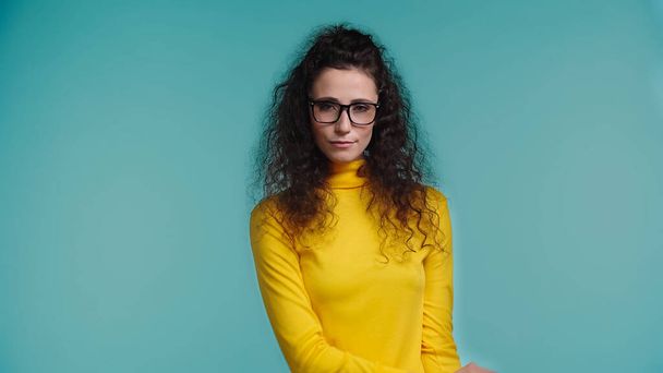 young woman in glasses and turtleneck standing isolated on blue - 写真・画像