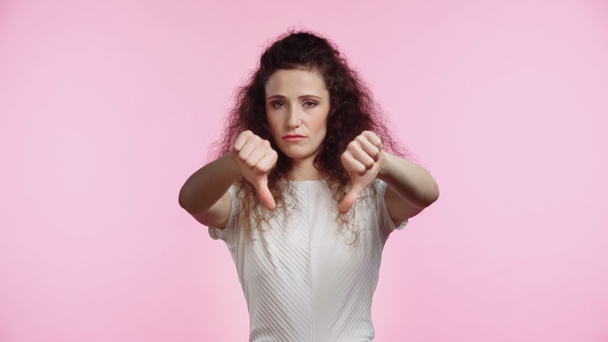 mujer joven disgustado mostrando pulgares hacia abajo aislado en rosa - Foto, Imagen