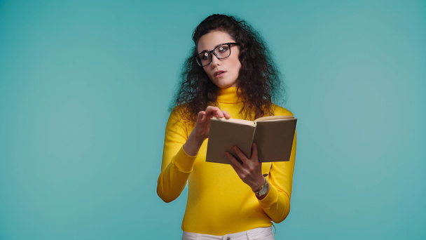 bored woman in glasses reading book isolated on blue - Foto, imagen