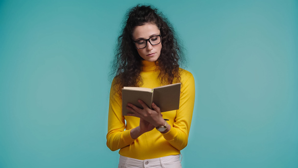mujer joven y enfocada leyendo libro aislado en azul  - Foto, Imagen