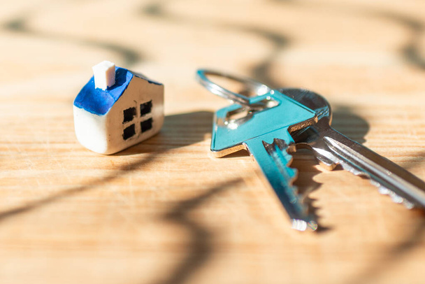 Miniatuur nieuw huis met huis twee sleutels op houten achtergrond, vastgoed en onroerend goed zakelijke concept.Close-up, selectieve focus. - Foto, afbeelding