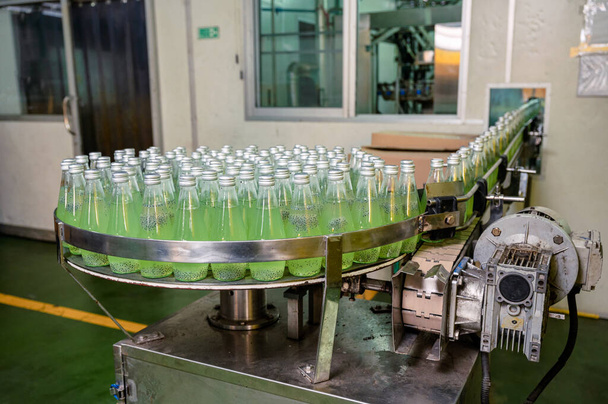 Prodotto di succo verde imbottigliato sul nastro trasportatore con macchina automatica nella fabbrica di lavorazione delle bevande - Foto, immagini