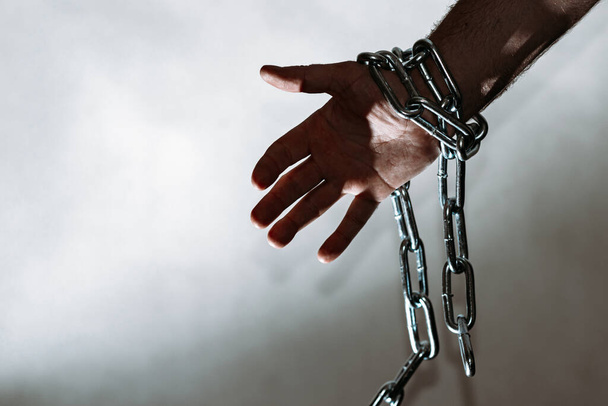 Hand with chain hang,chain in hand,the chain wound on the hand,gray background.Copy space. - Foto, Imagem