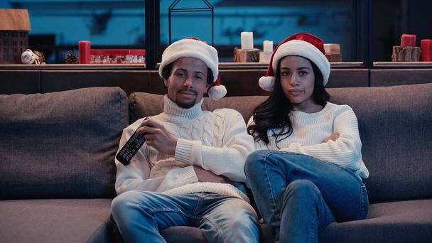 African american man watching movie with bored girlfriend in santa hat - Photo, Image