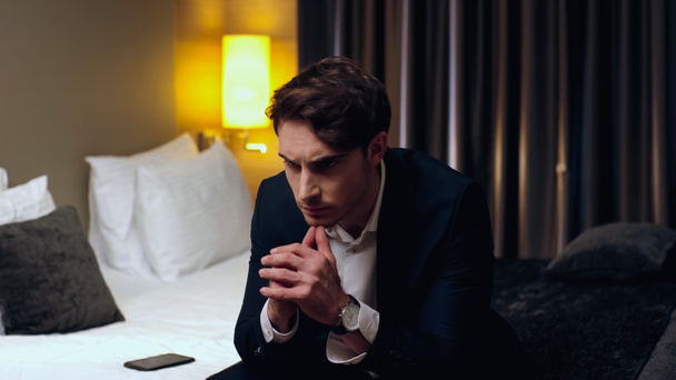 pensive businessman sitting on bed in hotel room - Zdjęcie, obraz