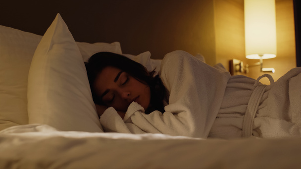 surface level view of young woman sleeping in hotel bed at night  - Foto, Imagem