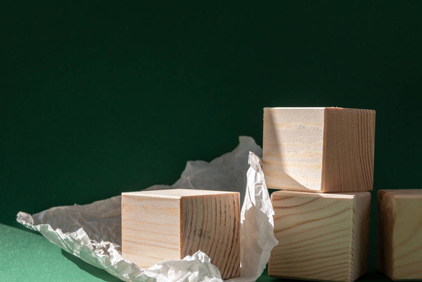 cubos de madera con papel desgarrado bodegón fondo verde esmeralda - Foto, imagen