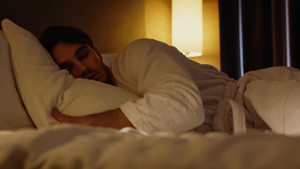 επίπεδο επιφάνειας του νεαρού άνδρα που κοιμάται στο κρεβάτι στο δωμάτιο του ξενοδοχείου  - Φωτογραφία, εικόνα