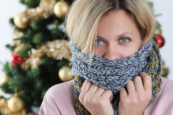 Portrait of young woman wrapped in scarf on background of Christmas tree - Photo, Image