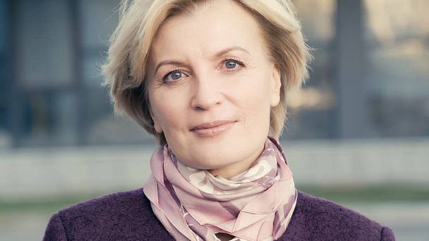 blonde middle aged woman in elegant neckerchief looking at camera outdoors - Foto, immagini