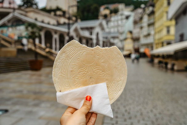 Beroemde Carlsbad wafer, CZ: lazenske oplatky, ontstaan in 1867. Vrouw hand met traditionele Tsjechische zoete koekjessnack gemaakt in Karlovy Vary, beroemde kuuroord op de UNESCO-lijst.Lekker eten achtergrond. - Foto, afbeelding