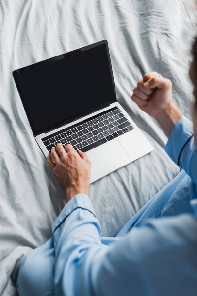 Yatakta dizüstü bilgisayar kullanırken pijamalı bulanık serbest çalışanın üst görünümü evet jestini gösteriyor   - Fotoğraf, Görsel