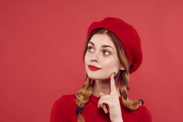 cheerful woman with a red cap on  head posing on  red background. High quality photo - Foto, afbeelding