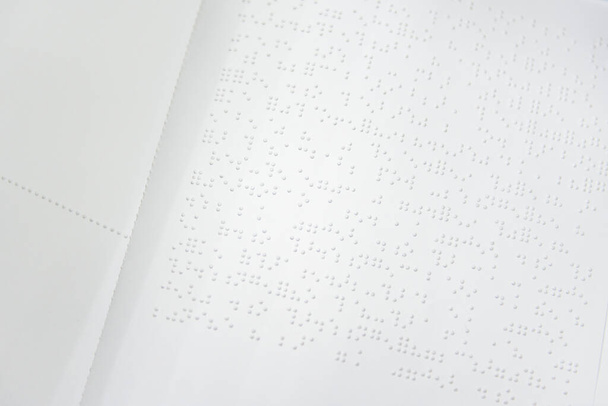 Fragment tekstu w języku Louisa Braille 'a wydrukowany na standardowej kartce papieru przy użyciu specjalnego sprzętu drukarskiego. - Zdjęcie, obraz