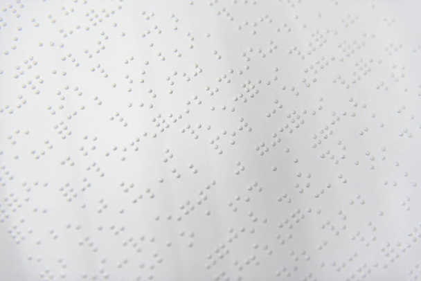Θραύσμα κειμένου στο Louis Braille τυπωμένο σε τυποποιημένο φύλλο χαρτιού με τη χρήση ειδικού εξοπλισμού εκτύπωσης. - Φωτογραφία, εικόνα