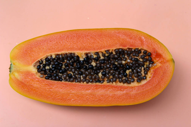 Half of topical fruit papaya with black seeds on pink background. Top view  - Fotoğraf, Görsel