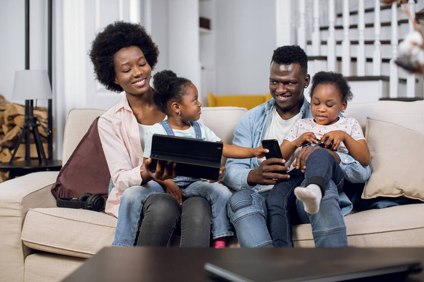 Cheerful african family playing games on tablet at home - Foto, Imagem