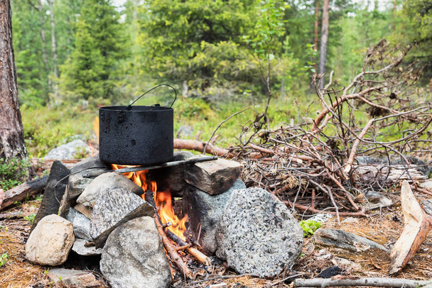 Gotowanie posiłku w garnku na ognisku podczas dzikiego kempingu w lesie - Zdjęcie, obraz