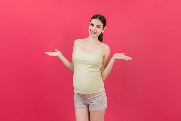 gelukkig verrast zwangere vrouw poseren geïsoleerd over gekleurde achtergrond. kopieerruimte. - Foto, afbeelding