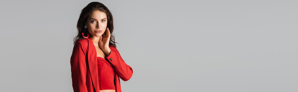 young woman in red suit and earrings posing isolated on grey, banner - Photo, Image