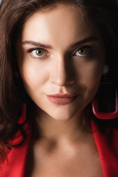 close up of young woman in red earrings looking at camera - Photo, image