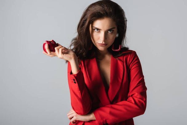 γυναίκα σε μοντέρνο κοστούμι κρατώντας κόκκινο μήλο απομονώνονται σε γκρι  - Φωτογραφία, εικόνα