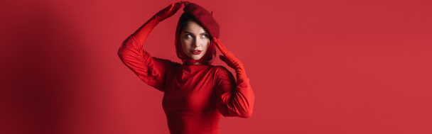 young brunette woman in beret posing while looking away on red, banner - Fotoğraf, Görsel