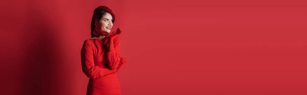cheerful and elegant woman in beret and dress posing on red, banner - Foto, Imagem