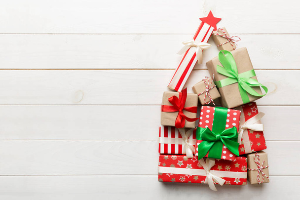 Рождественская елка из красиво обернутых подарков на цветном фоне, вид сверху. Новогодняя подарочная коробка. - Фото, изображение