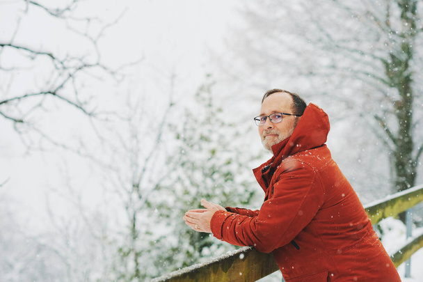 中年男性の屋外肖像画、 55 - 60歳、素敵な寒い日を楽しんで、赤いオレンジの冬のジャケットを着て - 写真・画像