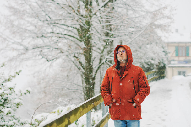 Retrato al aire libre del hombre de mediana edad, 55 - 60 años, disfrutando de un buen día frío, vistiendo chaqueta de invierno naranja roja. - Foto, imagen