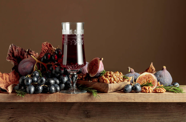 Vin de dessert rouge avec figues, noix et raisins bleus sur une table en bois. Espace de copie. - Photo, image