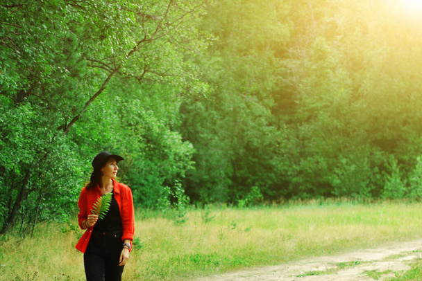 帽子を被った女性が夏に森を歩く。都会の喧騒から屋外でのレクリエーションは - 写真・画像