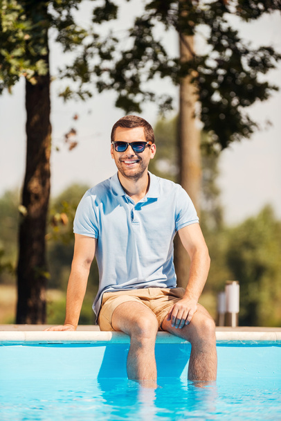 Man in sunglasses sitting by the pool - 写真・画像
