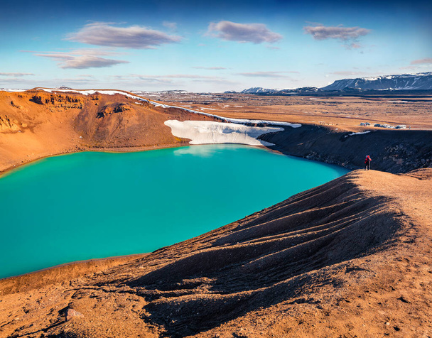 Турист, стоящий на берегу скалы на кратере Крафла Вити. Солнечная летняя сцена Исландии, Европы. Концепция образа жизни путешественников. Аэрофотосъемка - Фото, изображение
