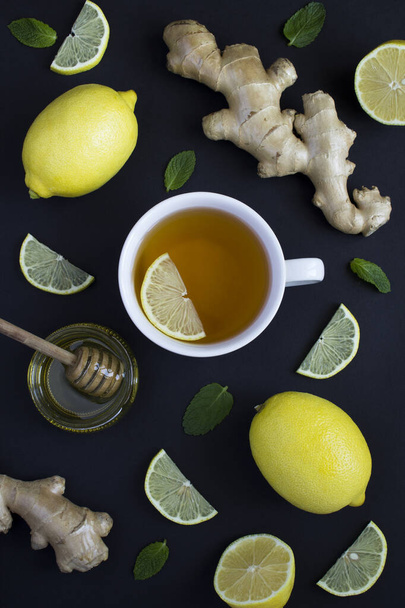 Top view of tea in the white cup with lemon, ginger and honey on the wooden background. Copy space. - Photo, image