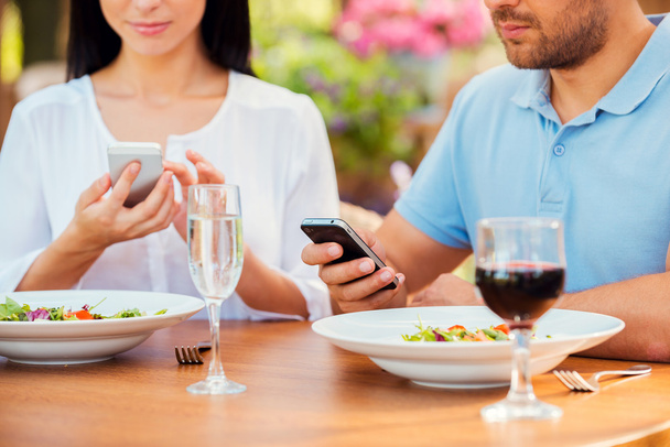 Couple typing on smart phones in restaurant - Photo, image