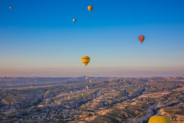 Hot air balloons flying over the valley at Cappadocia, Turkey. Goreme Balloon Festival. Beautiful hot air balloons take off at sunrise. Hot air balloons in the blue sky - Photo, image
