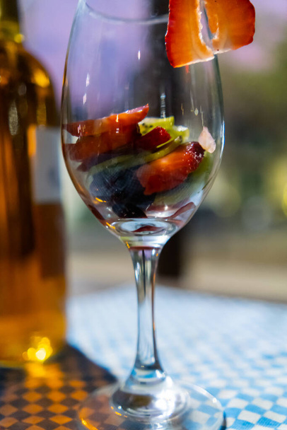 Weinglas mit Erdbeer-Kiwi-Scheiben auf einer karierten Tischdecke - Foto, Bild