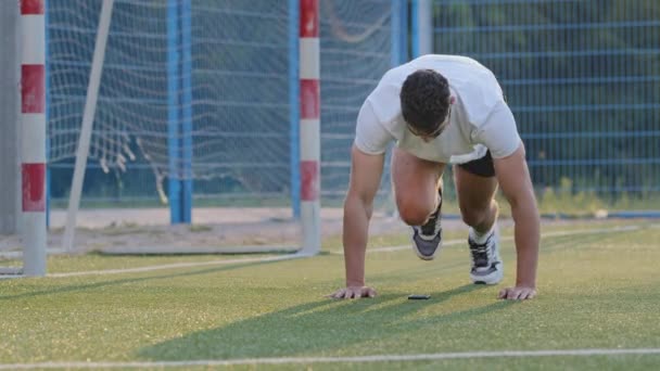 Midden-Oosterse voetballer traint benen, houdt fit door dagelijkse stadiontraining, bereidt zich voor op wedstrijd of kampioenschap. Millennial voetbal atleet Indiase man in de zomer sportkleding doen been lift oefening - Video