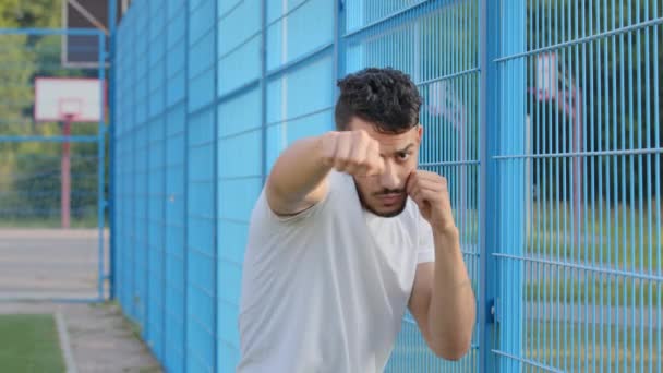Genç boksör, boksör, güreşçi veya futbol fanatiği yumruklarını sıkmış el sallıyor, Arap İspanyol erkek atlet darbe gösterileri dövüş tekniklerini gösteriyor. Orta Doğulu Hintli adam stadyumda antrenman yapıyor. - Video, Çekim