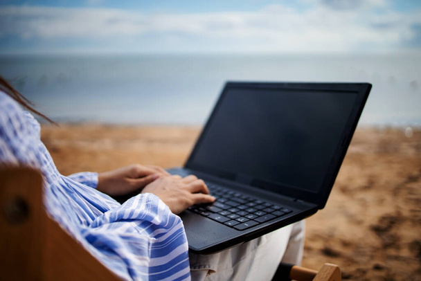 熱帯のビーチ休暇中にタブレットコンピュータを持つ若いアジアの女性。サンラウンジャーに寝そべってノートパソコンで働くフリーランス. - 写真・画像