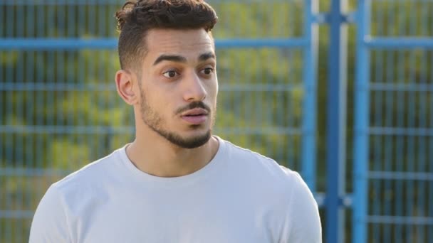 Gülümseyen Arap genç erkek futbol koçu veya spor tişörtü fanatiği duygusal olarak maçı takip ediyor, oyuncuları selamlıyor, onaylayıcı bir şekilde başını sallıyor, seviniyor. Orta Doğulu Hintli futbolcuları destekliyor. - Video, Çekim