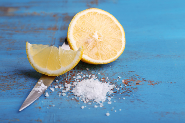 Still life with fresh lemon, knife and salt on old wooden table - Фото, изображение