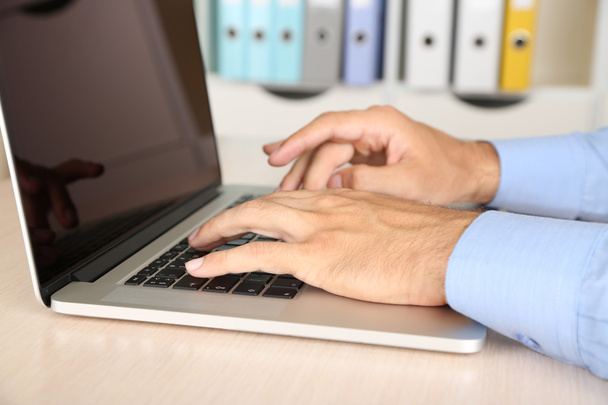 Man working on laptop on wooden table on folder background - Foto, Imagem