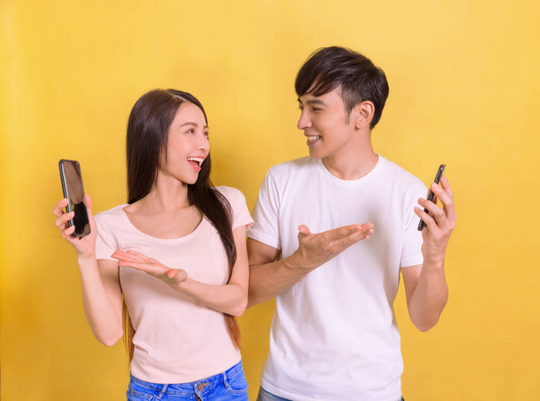 スマートフォンの画面を示す幸せな若いカップル - 写真・画像