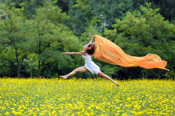 Гнучка жінка стрибає в повітрі, слідуючи шарфу
 - Фото, зображення