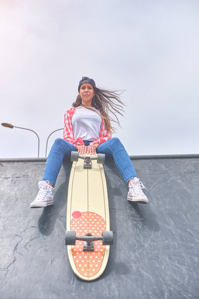 Mooie en mode vrouw poseren met een skateboard Jonge vrouw poseert met skateboard in de stad, vrouwelijke tiener outdoor met lange boord. - Foto, afbeelding