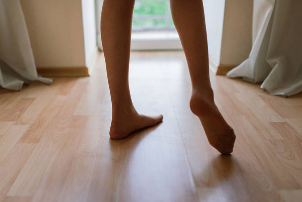Pernas nuas femininas, permanecendo na ponta dos pés, pele saudável e lisa, exercitando a manhã na janela. Fechar - Foto, Imagem