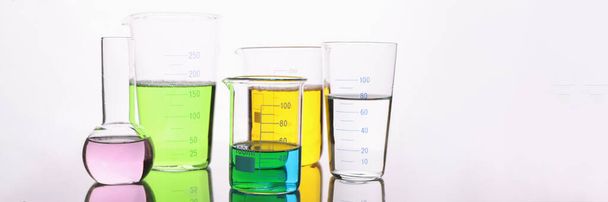 cristalería de laboratorio llena de líquido colorido sobre fondo blanco - Foto, Imagen